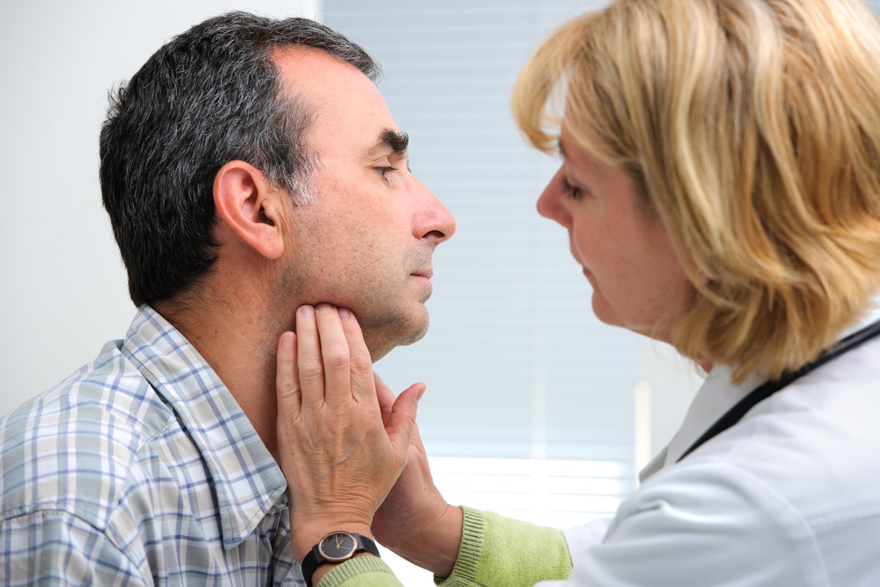 Female doctor performing an exam on a male patient's throat.