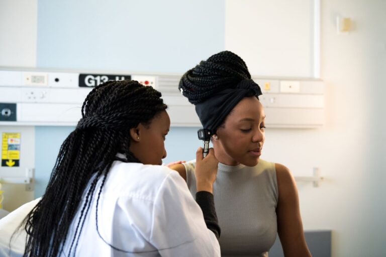 female doctor looking in female patients ear with a medical device to identify indications of an earache